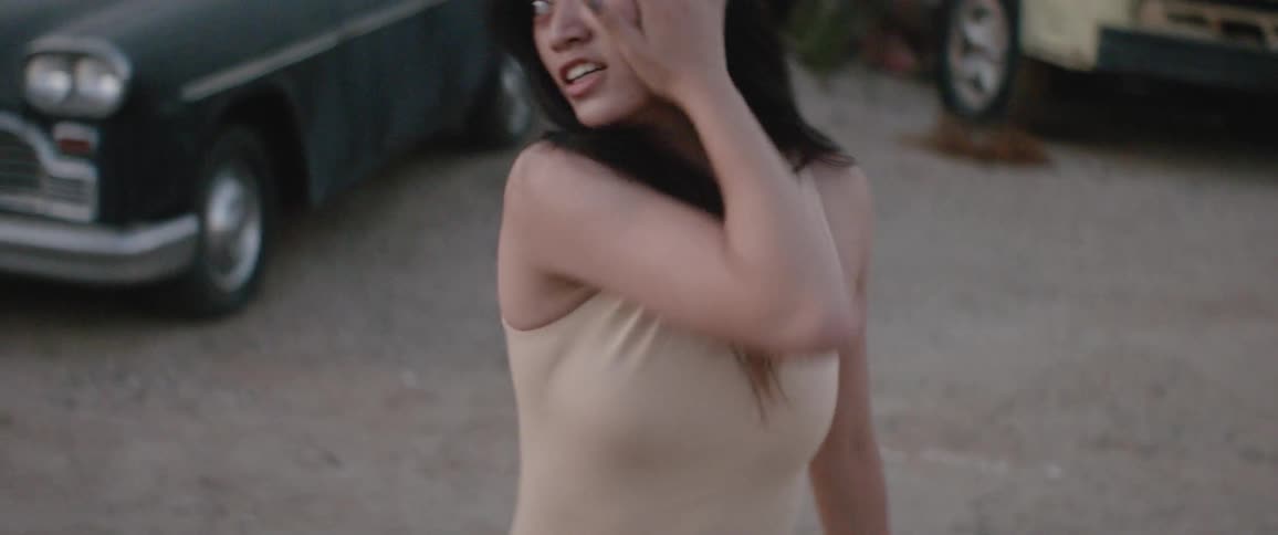 A woman dancing outside with cars in the background