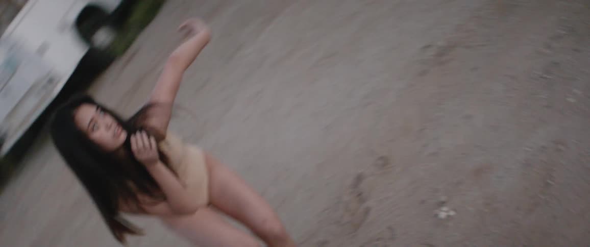 An asian woman dances in a car park