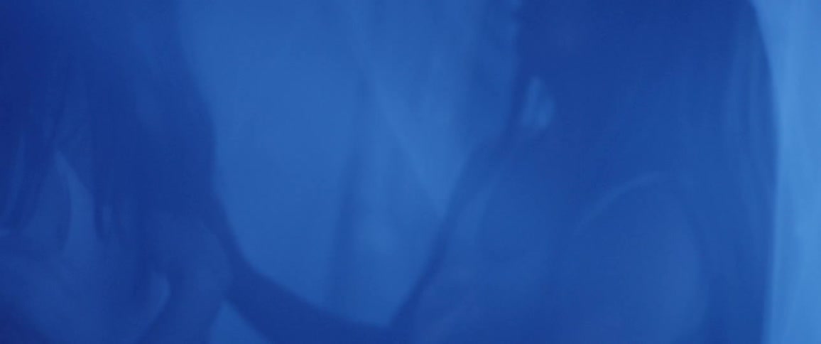 Two women dance together in a tent of veils and bluish light