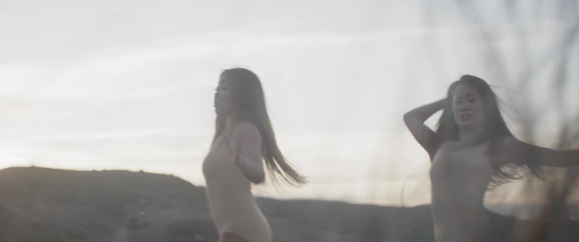 Two asian woman dance on the grass field at dusk