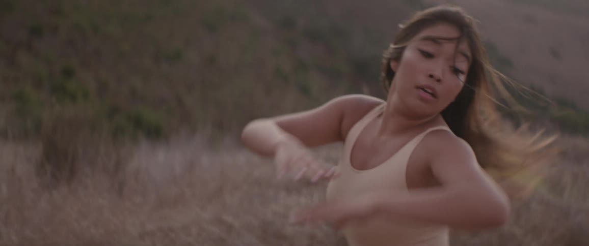 An asian woman dances outdoors