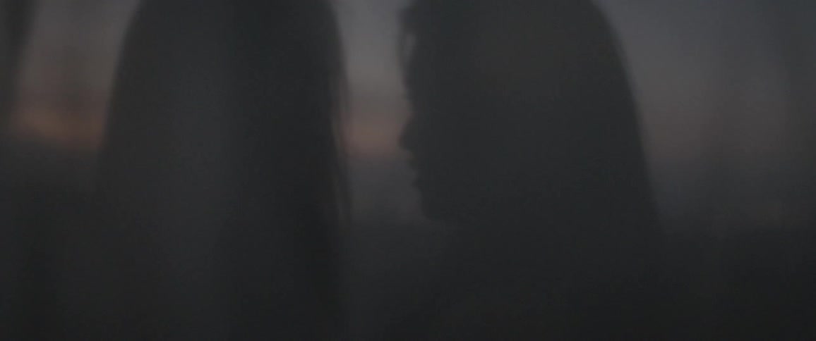 Two women talking behind a transparent curtain