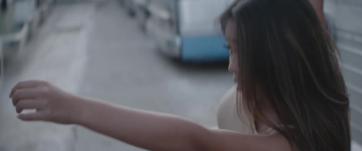 Asian woman dances between two vehicles in the junkyard during daylight