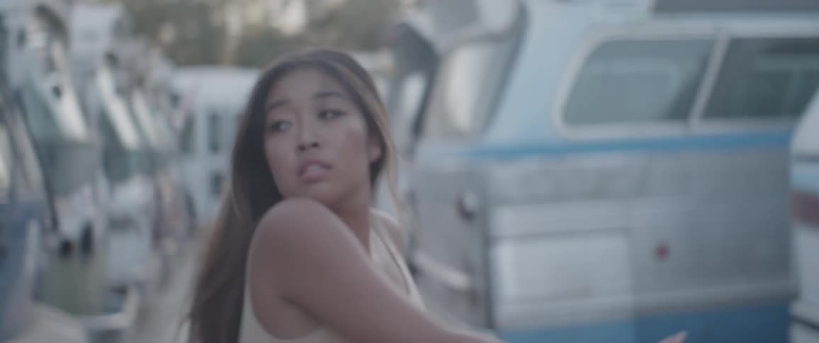 An asian woman dancing in vehicle yard