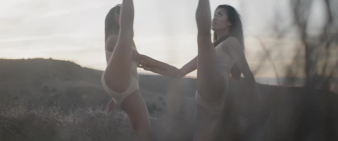 A woman grabs hold of another womans arm and then dance around each other