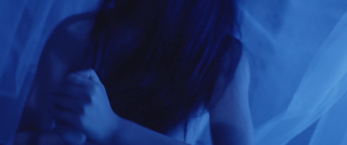 Women dance while surrounded by hanging sheer fabric in a blue light