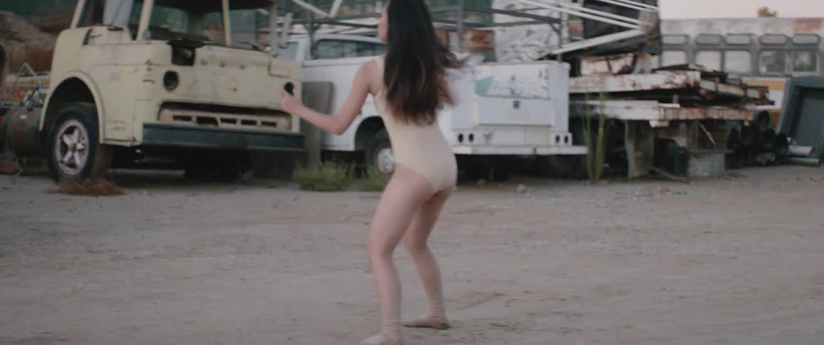 Asian woman dances in the junkyard during daylight