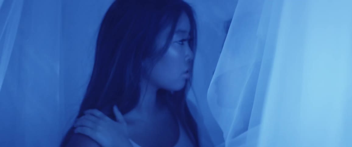 A woman is in a room with a person behind curtains