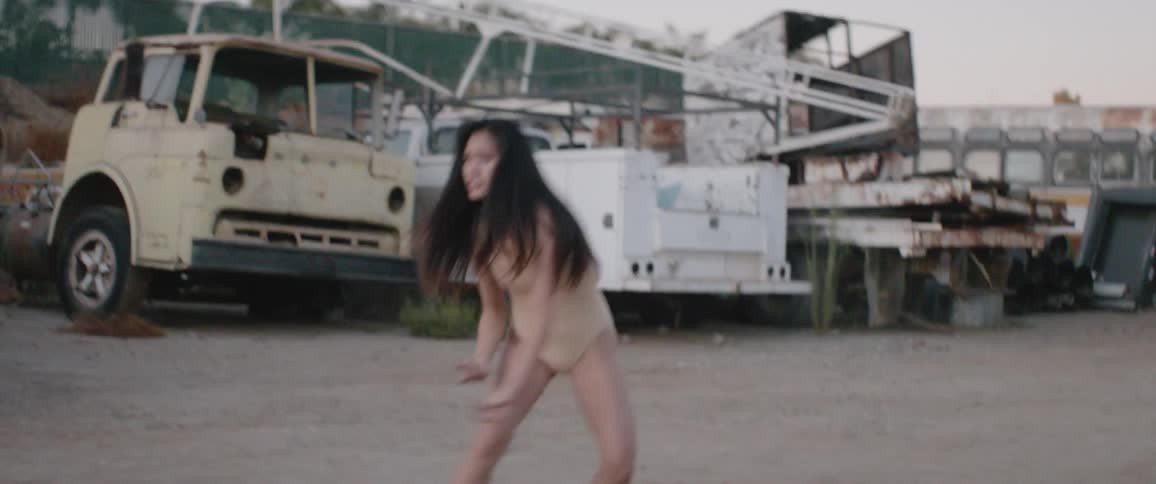 Asian woman dances in the junkyard during daylight