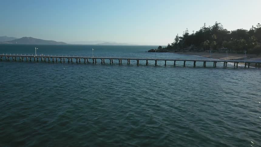 A long pier runs from the coast to the water