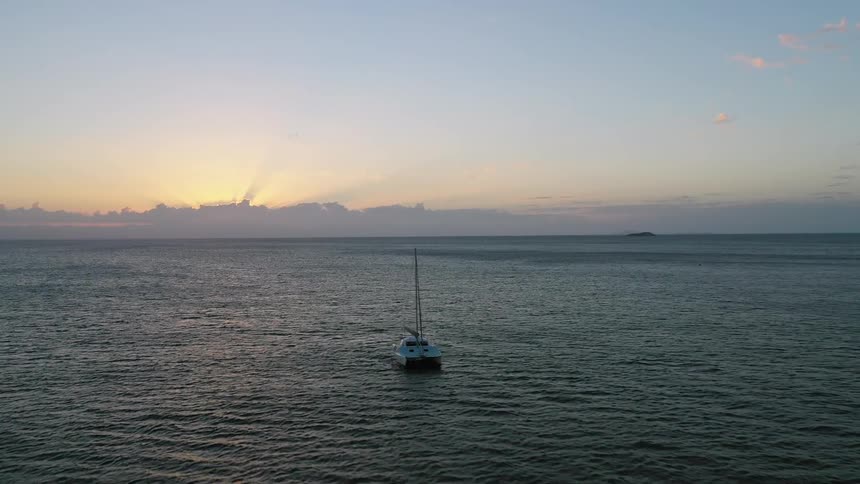 A small boat is at sea in calm waters at sunset