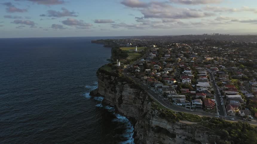 I birdseye view of an urban city on top of a cliff surrounded by ocean waters