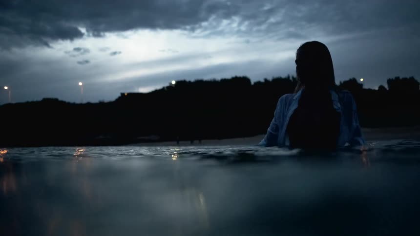 Silhouette of a woman standing in the sea under the moonlight fully clothed