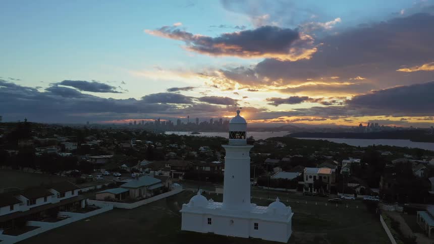 Lighthouse surrounded by city buildings at sunrise