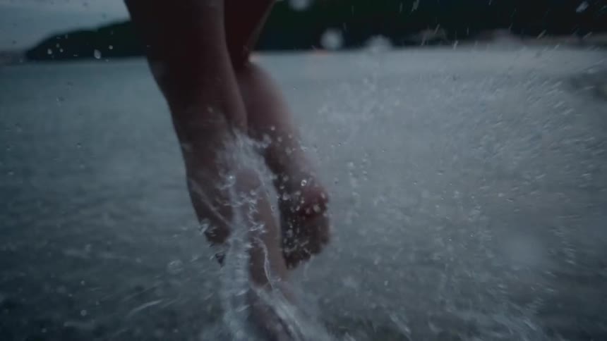 Woman running into ocean at night