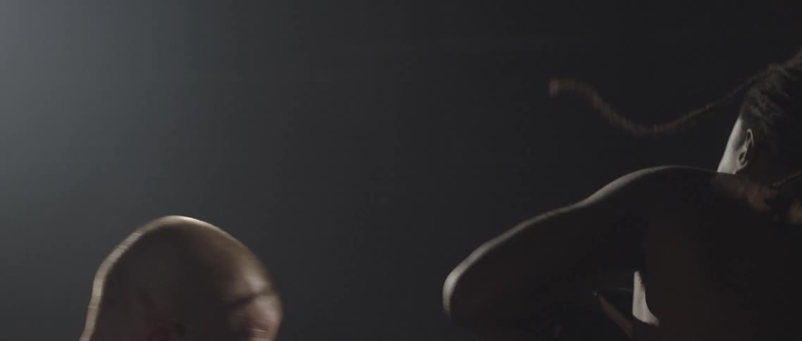 White boxer and black boxer hit each other in the ring under the light