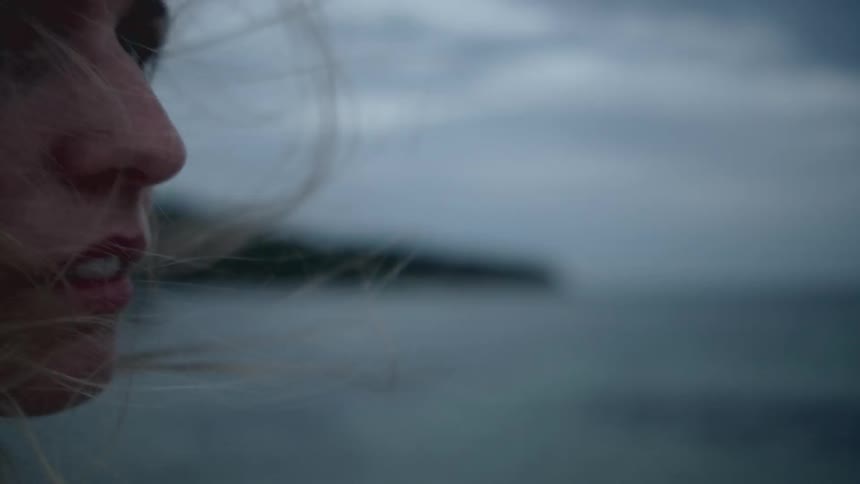 Long hair blonde woman looks back over the shoulder on a cloudy day next to the beach