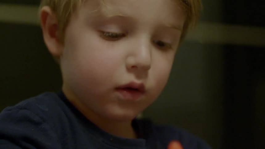 A little boy smiles at something he is playing with