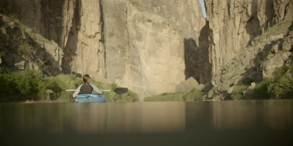 A woman is kayaking down a river