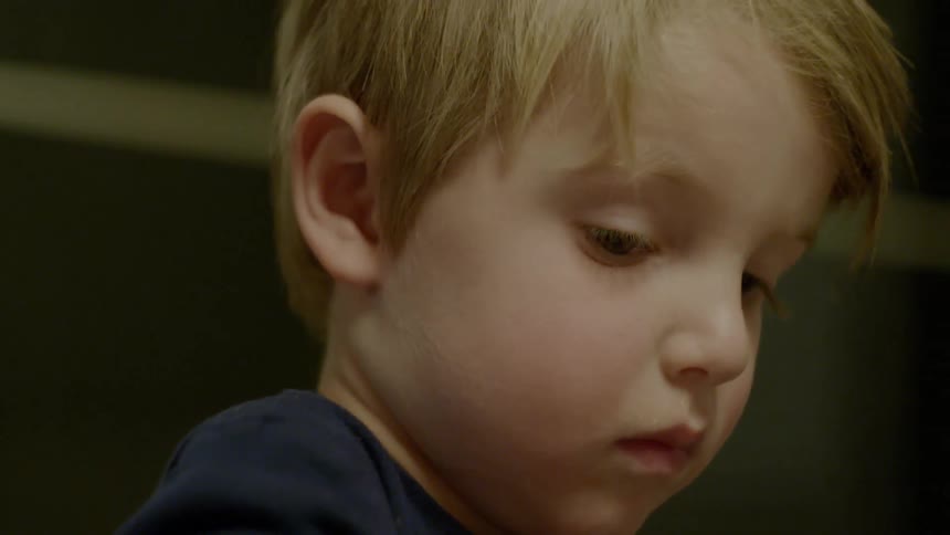 Child looks down indoors at night