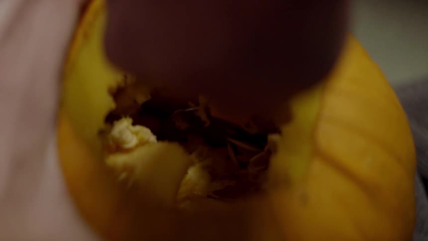 Seeds and inside of a pumpkin being scooped out