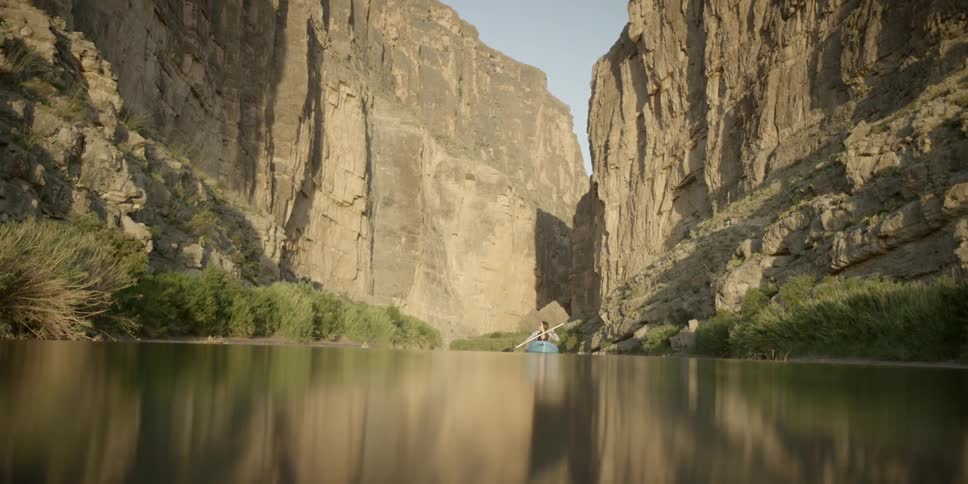 Woman paddling in a canoe through the canyon on a calm river