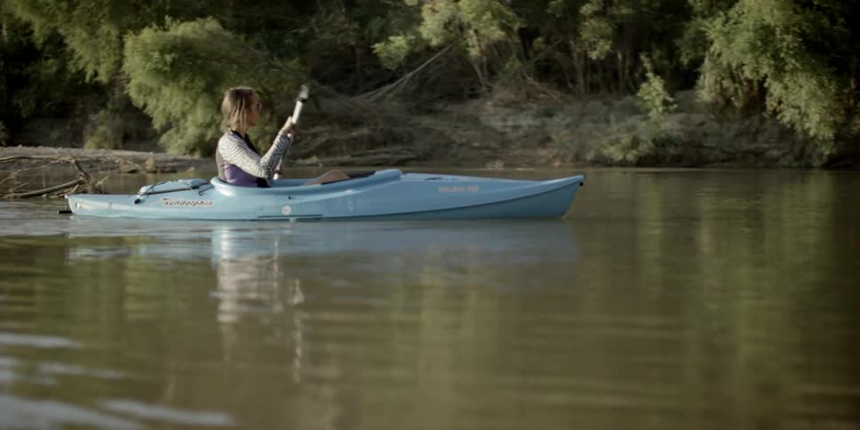 A young girl rows a kayak