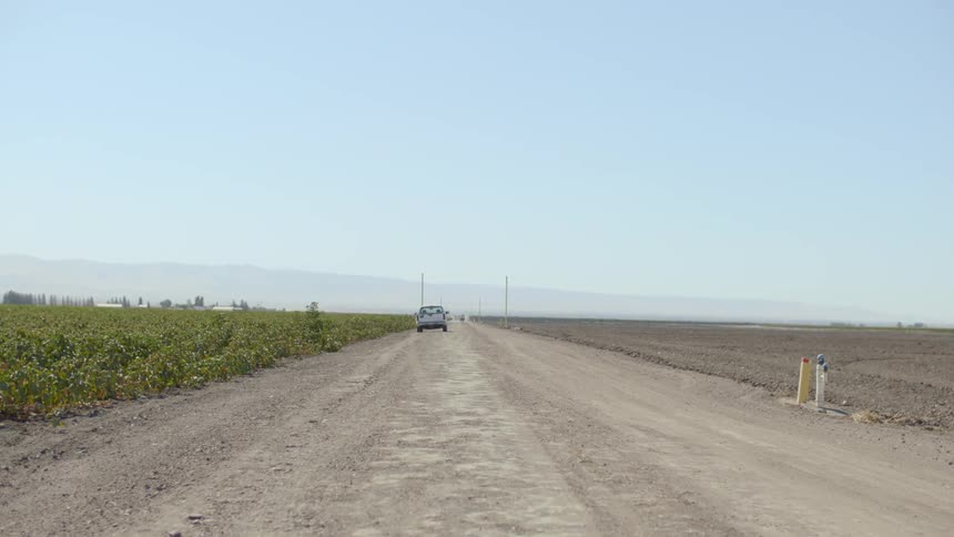 A vehicle parked on the side of a dirt road with pipes sticking out of the ground