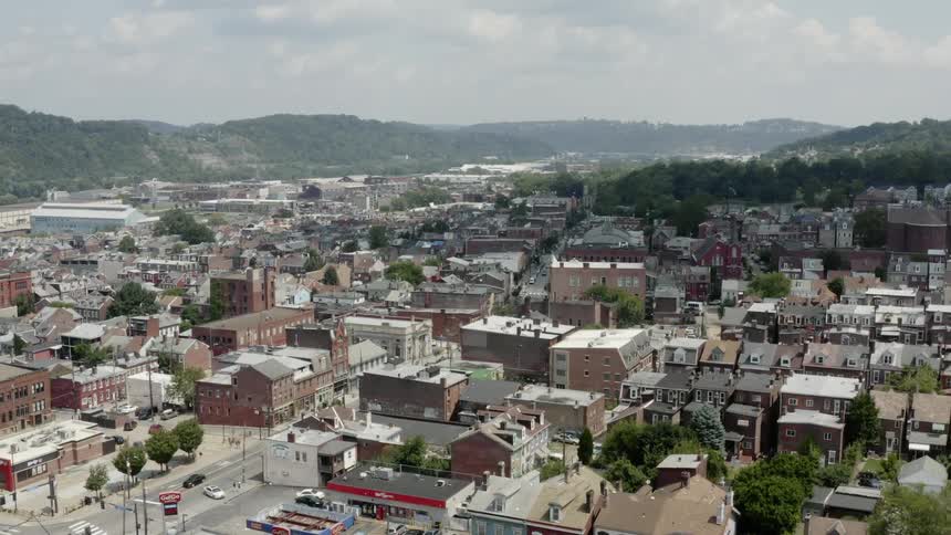 A suburb full of buildings and homes surrounded by hills and a river