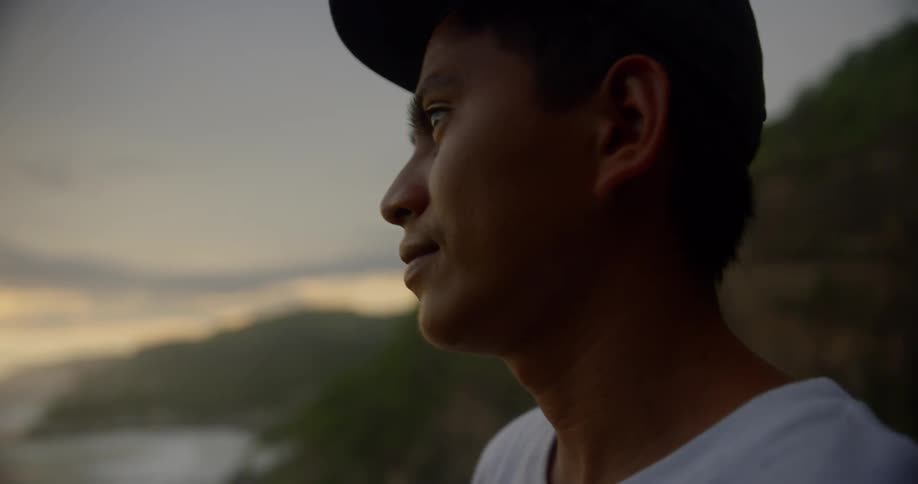 A man is looking outdoors at the sunset