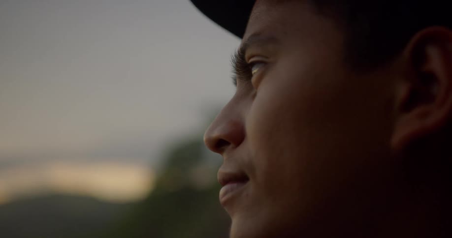 Man wearing cap looks ahead at dusk