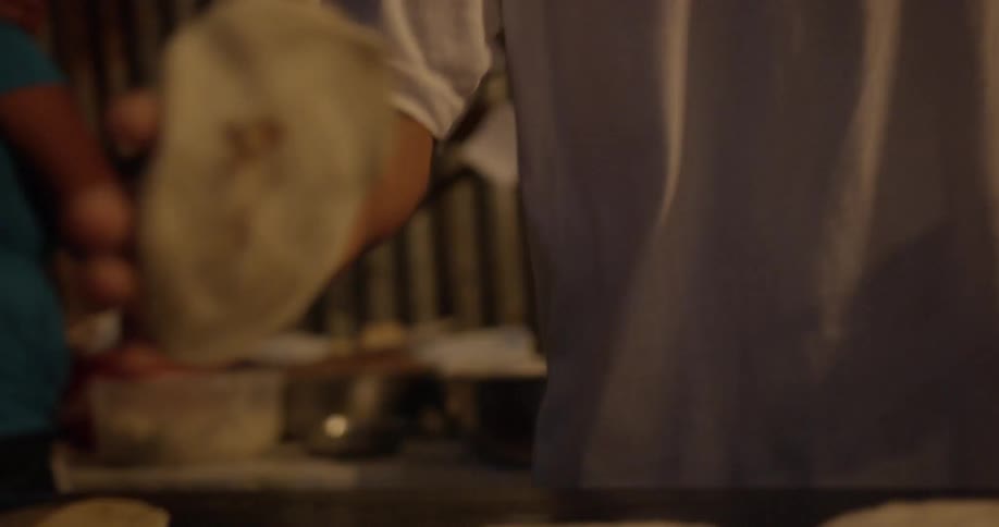 A man preparing flat bread dough to cook on a griddle