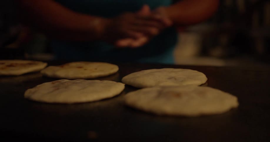 A cook slaps dough on a grill