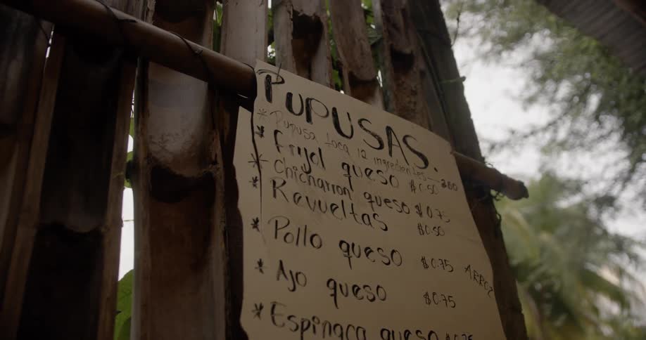 A menu for food hung on the wall of a bamboo structure