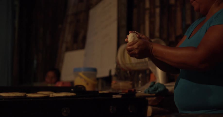 A woman rolls dough in her hands