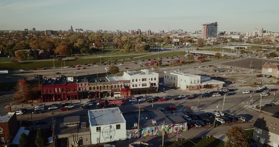 A multi lane highway runs through a busy urban sprawl with a row of shops in the foreground of the shot