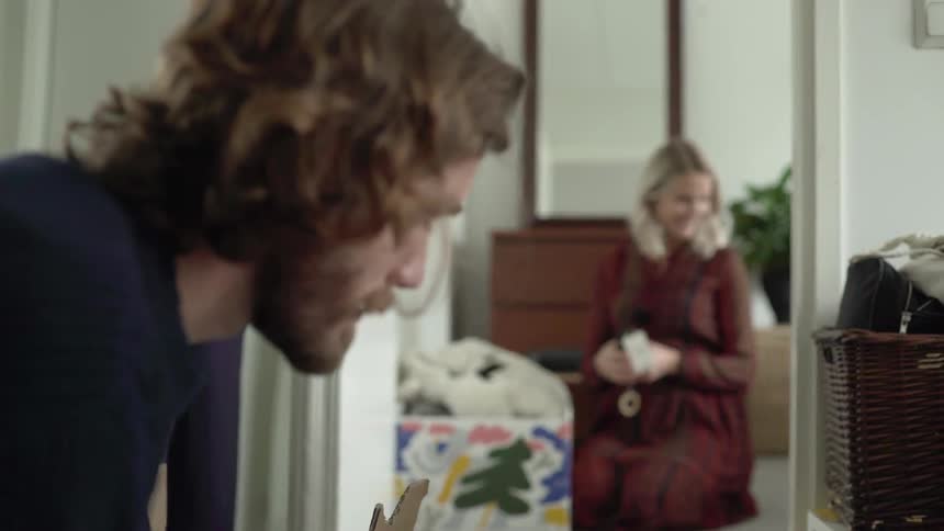Long hair bearded man and blonde pregnant woman pack clothes in the house during daylight