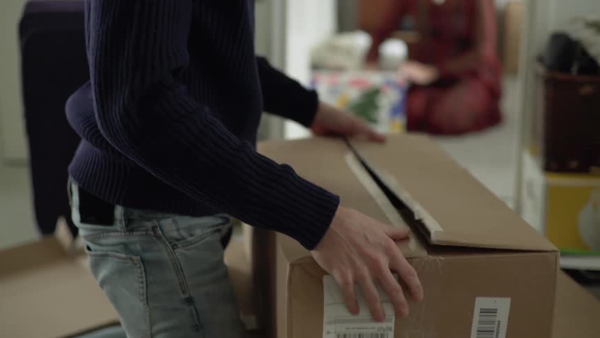 A man and a woman unpack boxes in a room