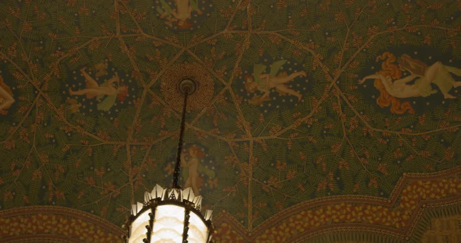 A light fixture hangs down from an ornately painted ceiling