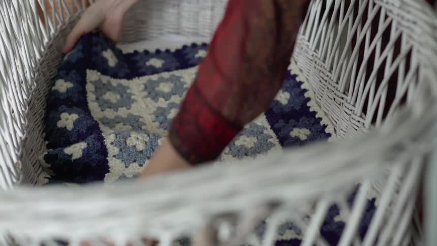 Patterned crochet blanket laid out in a white bassinet
