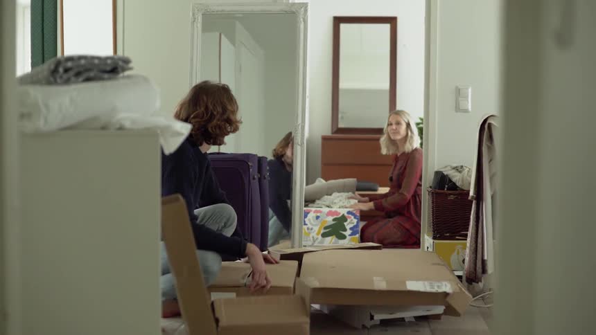A man restes a box on the floor then talks to a woman as she smiles