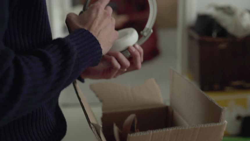 A man taking a headphones out of a cardboard box