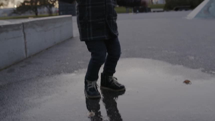 A child is jumping in a rain puddle outdoors