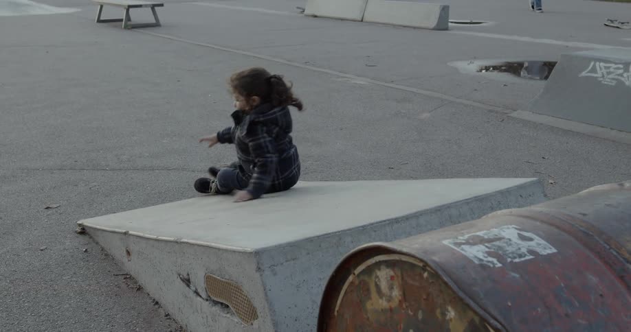 The little girl scooches on her bum then gets up and walks