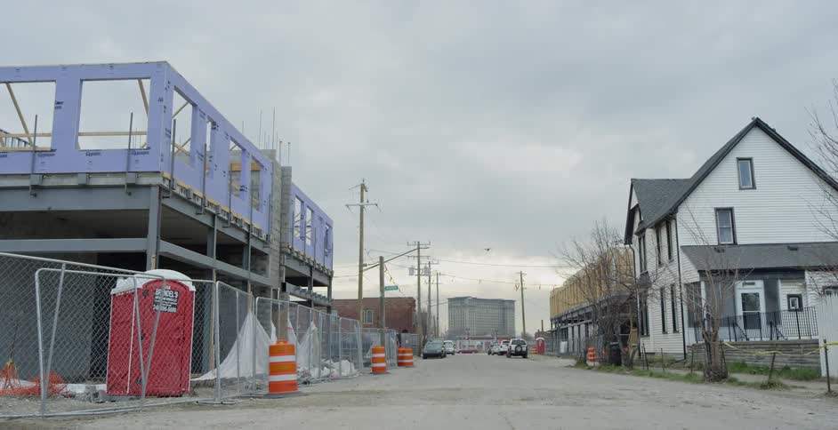 A building under construction has fencing and cones surrounding it