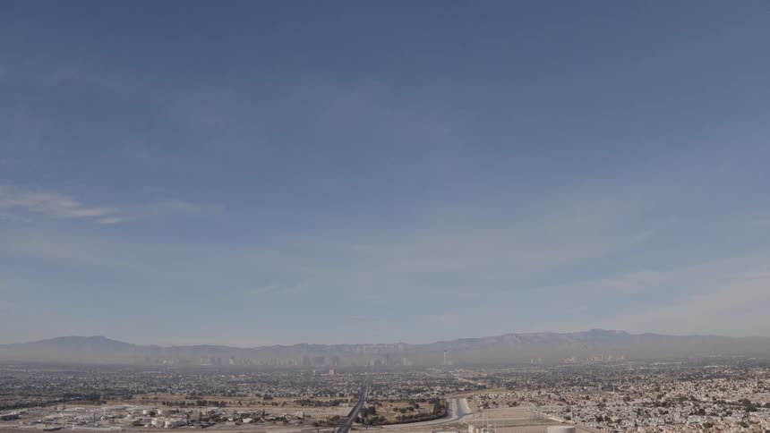 Large city and mountains sit under a blue sky