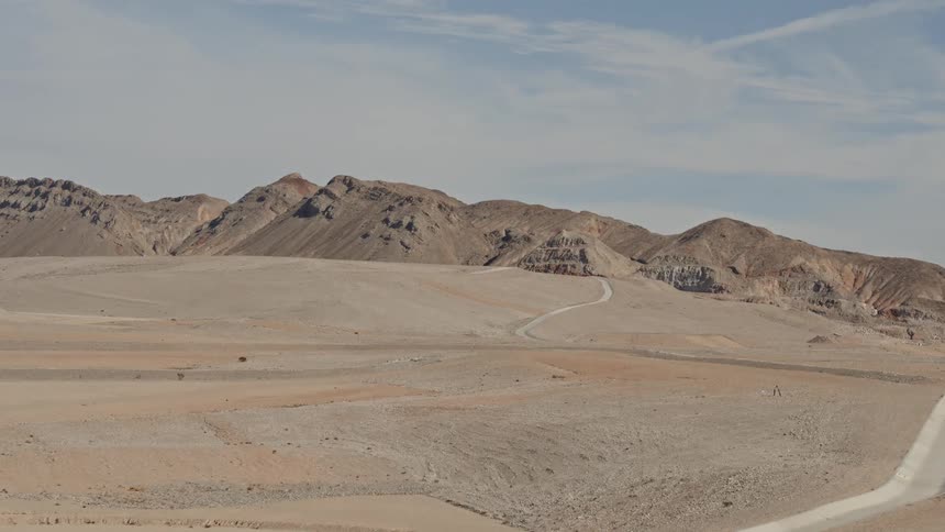 A drainage channel and road cut across the desert