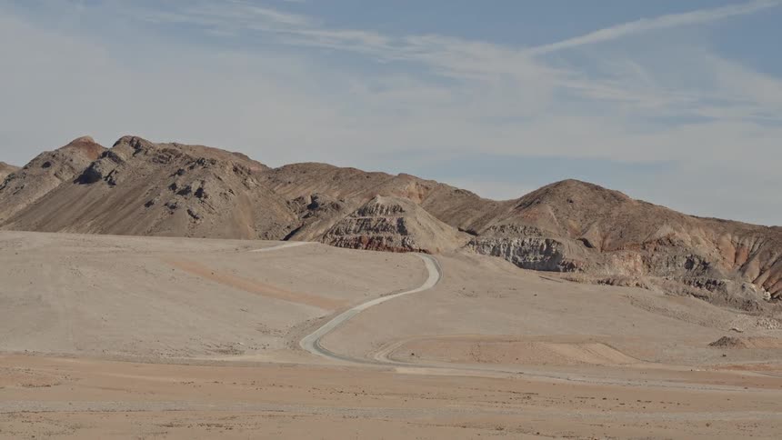 Road winds through desert toward rocky barren hills