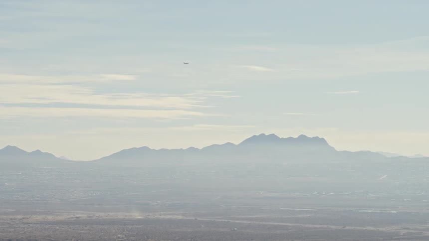 Fog covered mountains and plains under cloudy blue sky