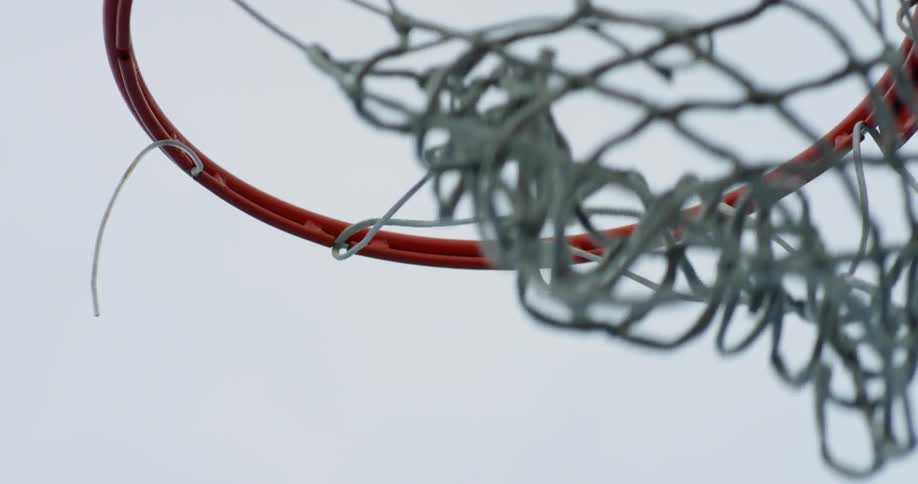 Basketball drops into a hoop outside on a cloudy day